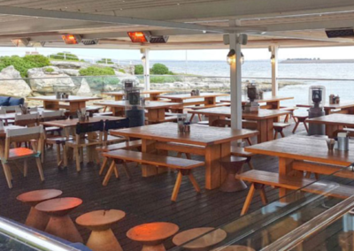 An image of a sleek and modern Heliosa infrared heater is mounted in a seafront bar.